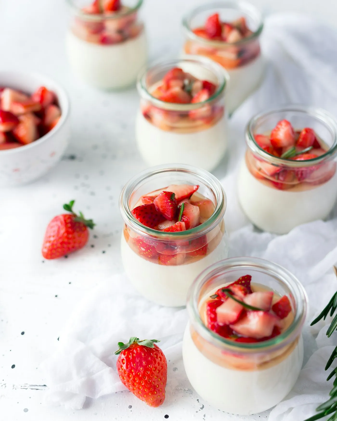 Sliced strawberries layered with cream in a clear glass jar