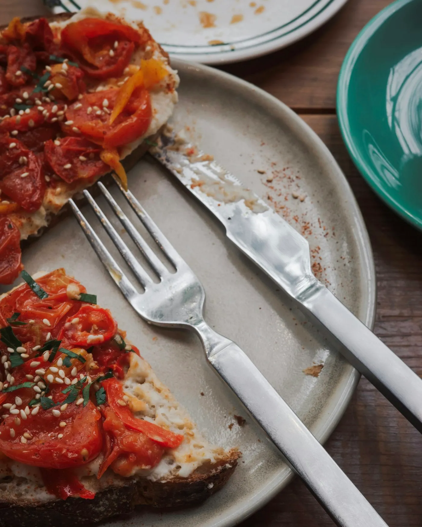 Two slices of toast topped with sliced tomatoes and sesame seeds