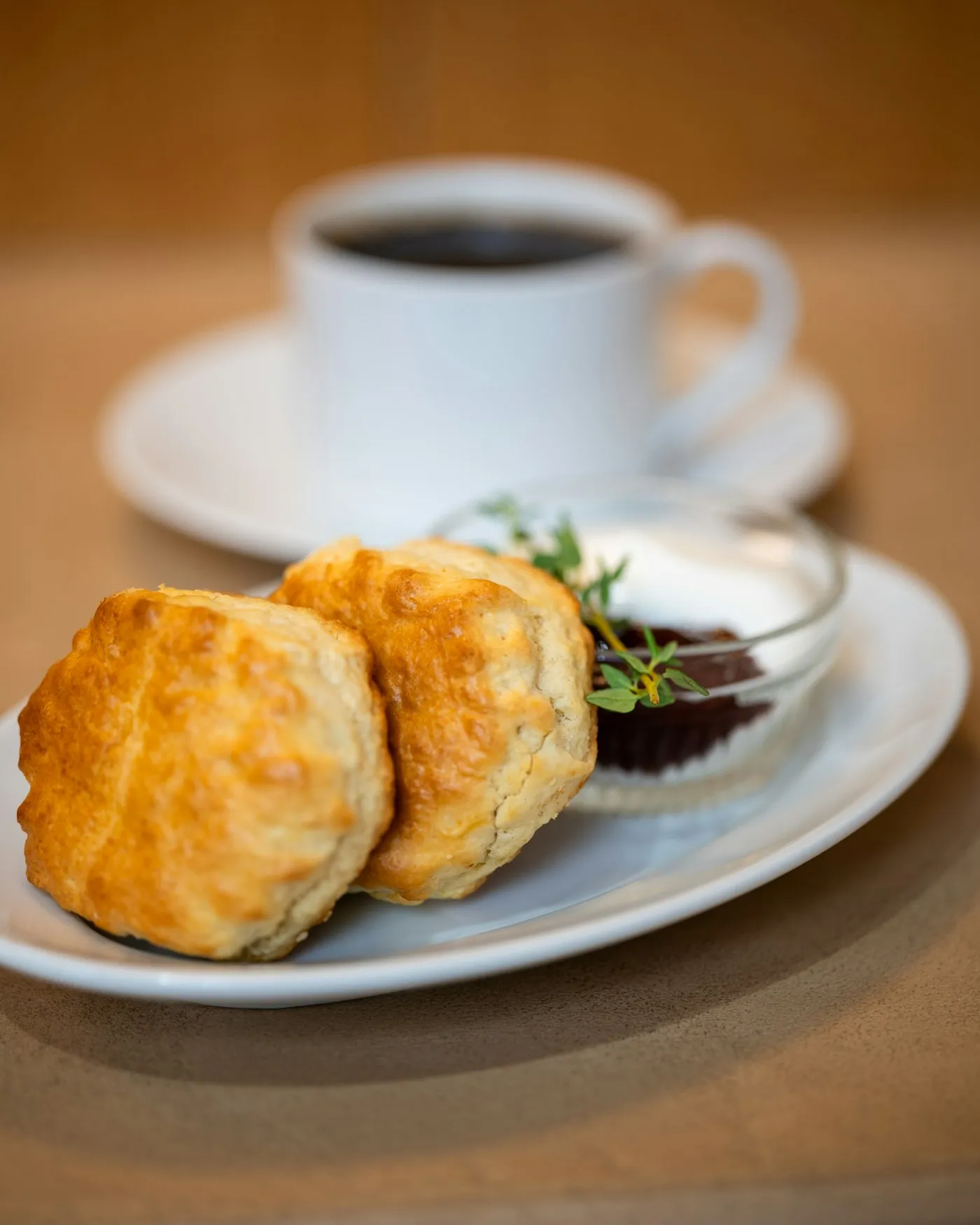 Scones on a plate with jam, cream and a cup of coffee