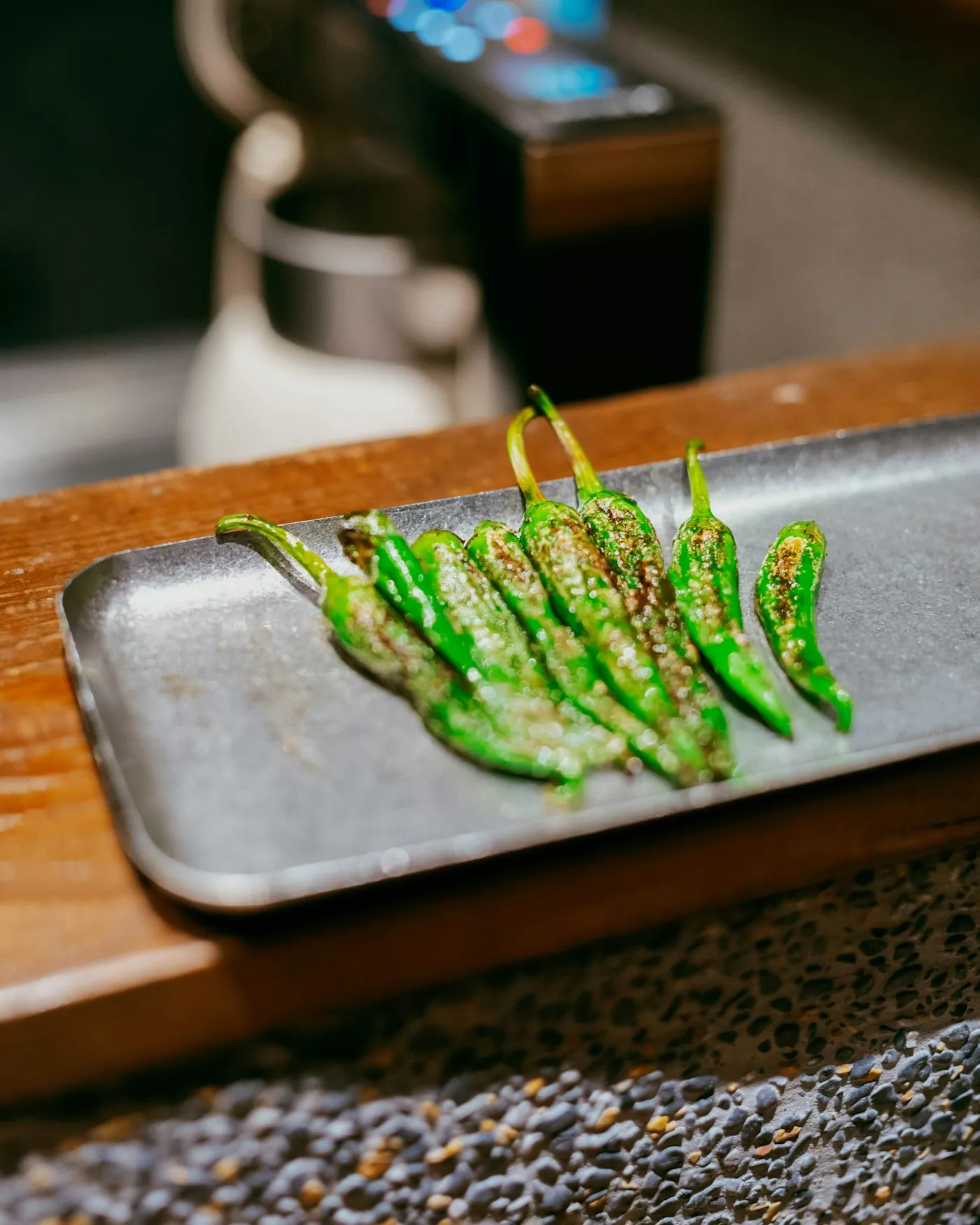 Grilled green peppers arranged on a dark rectangular plate