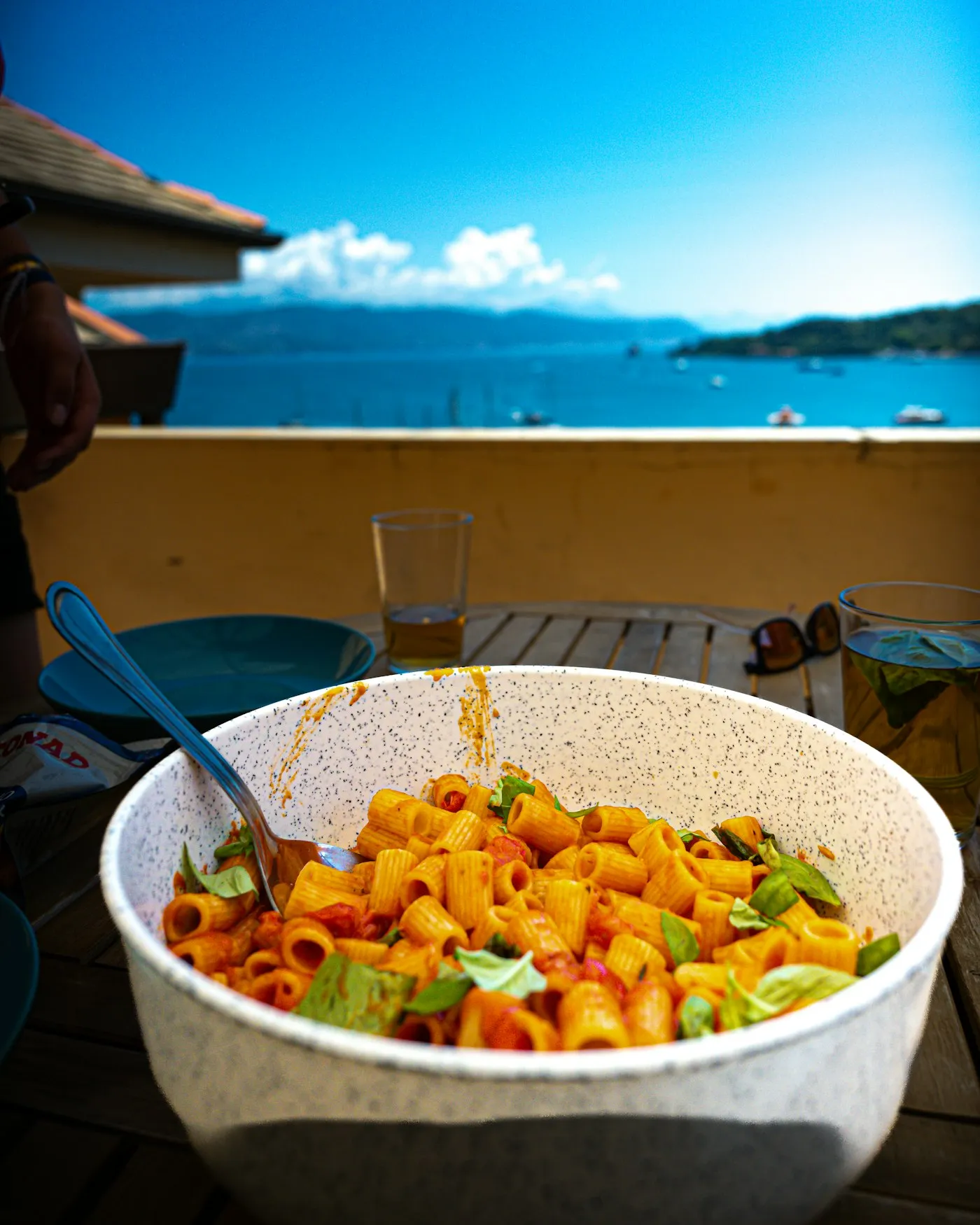 A bowl of rigatoni in tomato sauce on an outdoor table