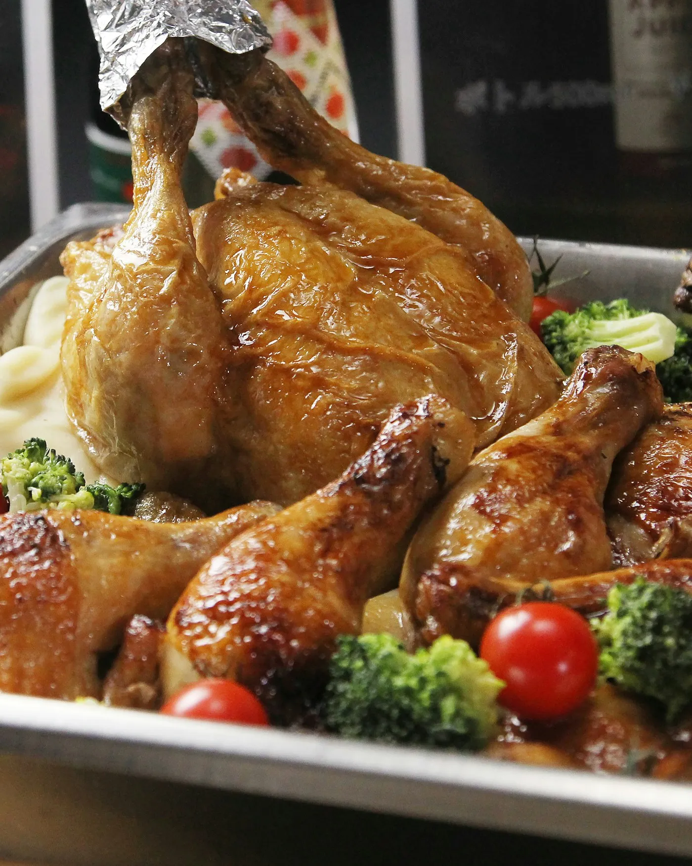 A roasted chicken on a serving dish with vegetables and mashed potatoes