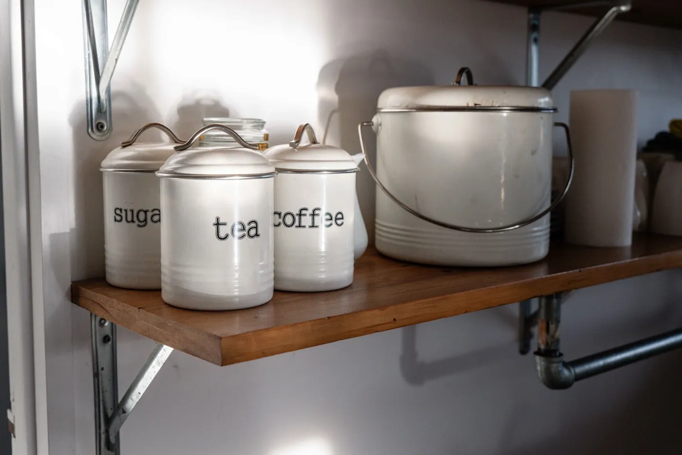 White canisters labelled sugar, tea and coffee on a shelf