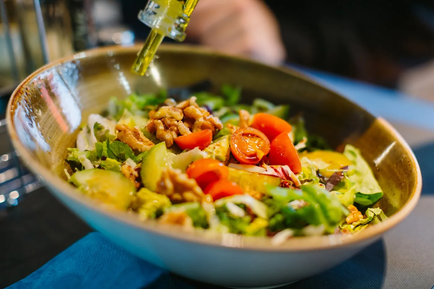 Olive oil being drizzled over a bowl of salad