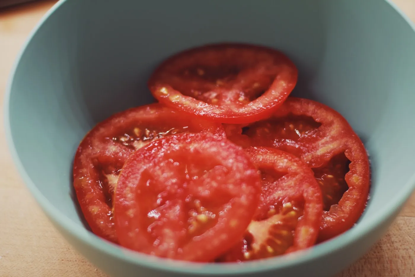 Thickly sliced tomatoes in a grey-green bowl