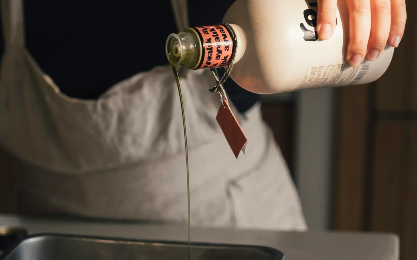Olive oil being poured from a bottle over food in a baking dish
